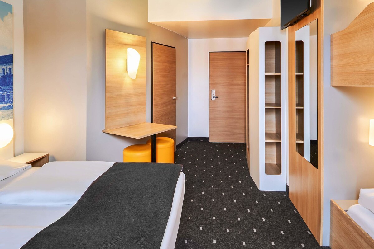 Une chambre d’hôtel comprenant un lit, un bureau, une chaise, une armoire et un téléviseur.