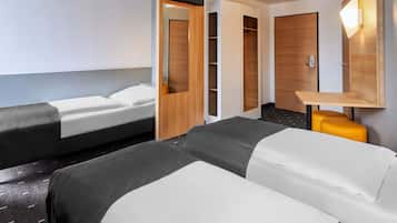 A hotel room with two beds, a desk, a wardrobe, and a TV.