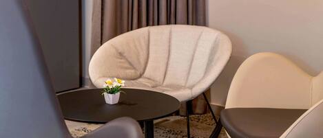Una habitación moderna con una mesa redonda, dos sillas y una planta pequeña sobre la mesa.