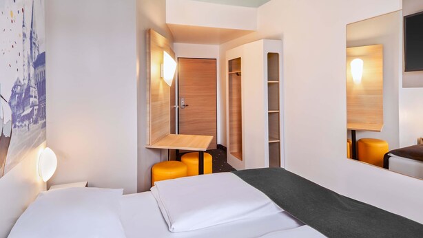 A hotel room with a bed, a desk, a chair, and a wardrobe. - B&B Hotel Mainz-Hbf (Mainz)