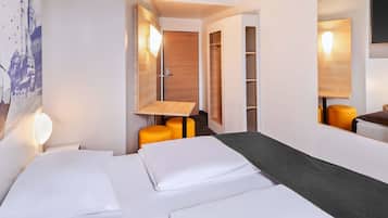 A hotel room with a bed, a desk, a chair, and a wardrobe.