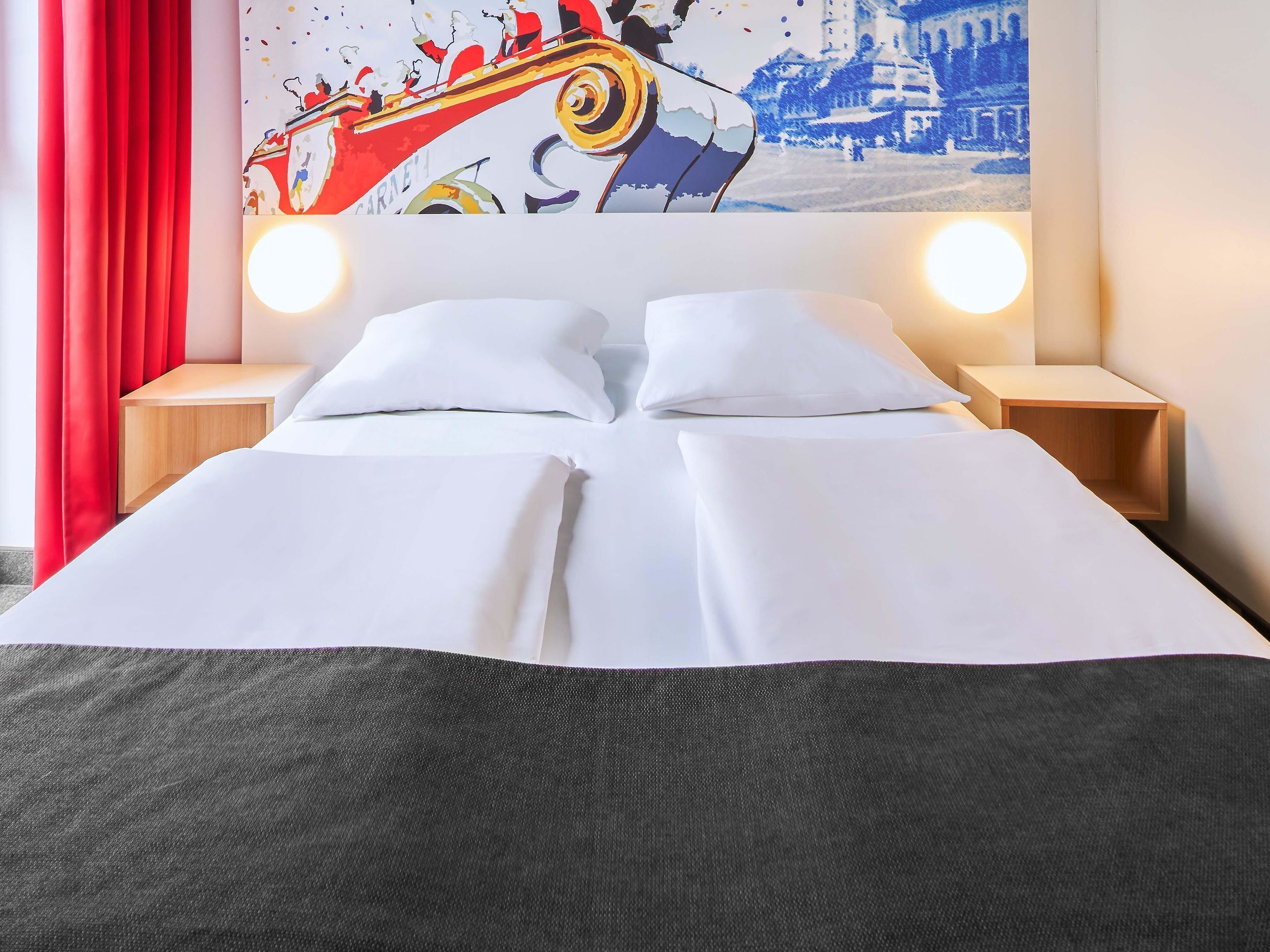 Ein Hotelzimmer mit einem Bett, zwei Nachttischen und einem großen Gemälde darüber.