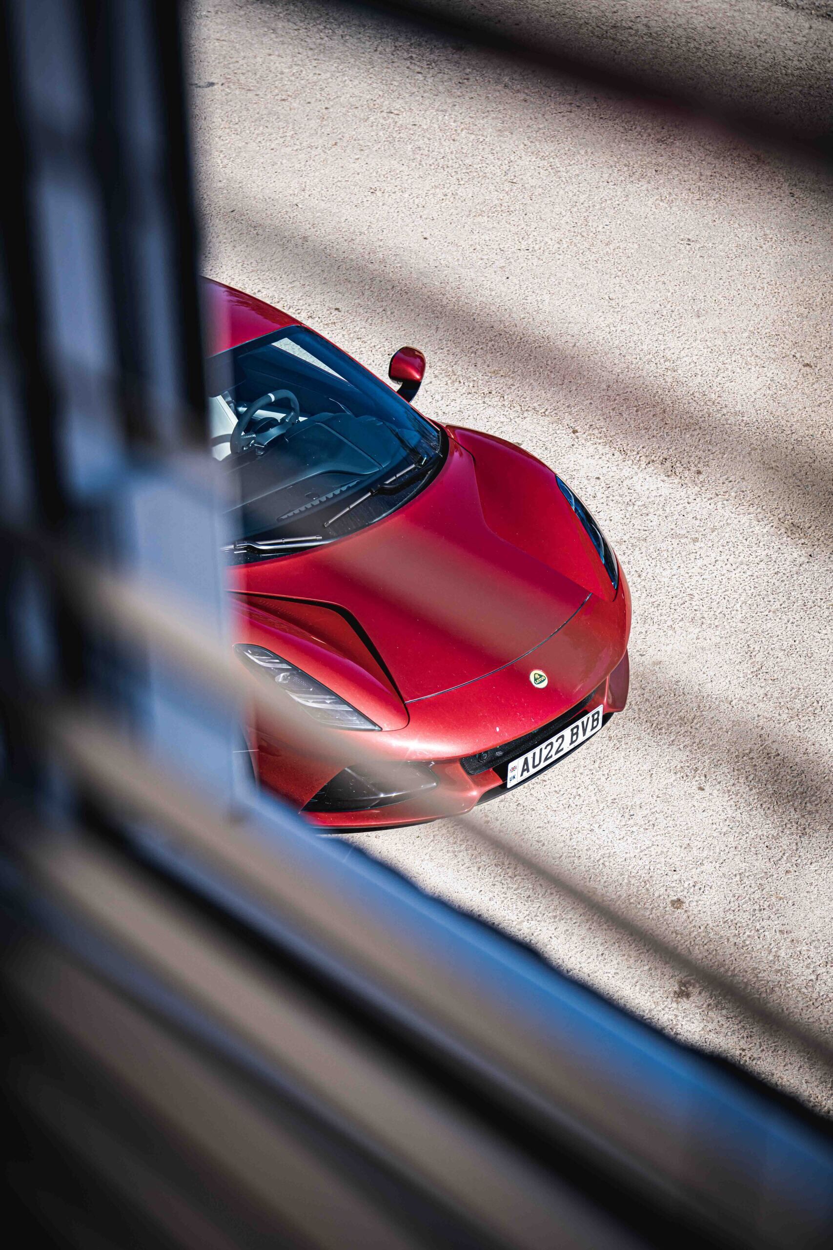 A red sports car parked on a sandy surface.