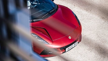 A red sports car parked on a sandy surface.