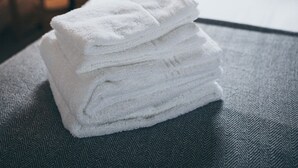 En snyggt bäddad säng med vita lakan och en randig kudde i ett hotellrum.