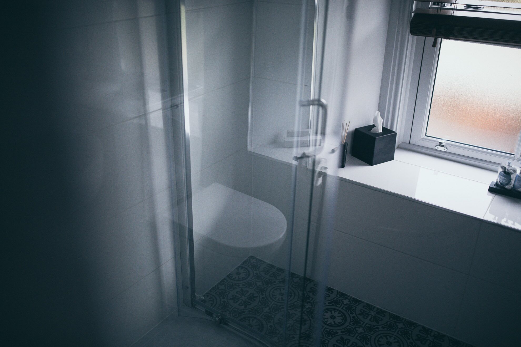 A bathroom with a glass shower enclosure, a toilet, and a window with a view.