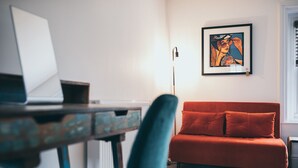 Ett rum med ett skrivbord, en röd soffa och ett inramat konstverk på väggen.