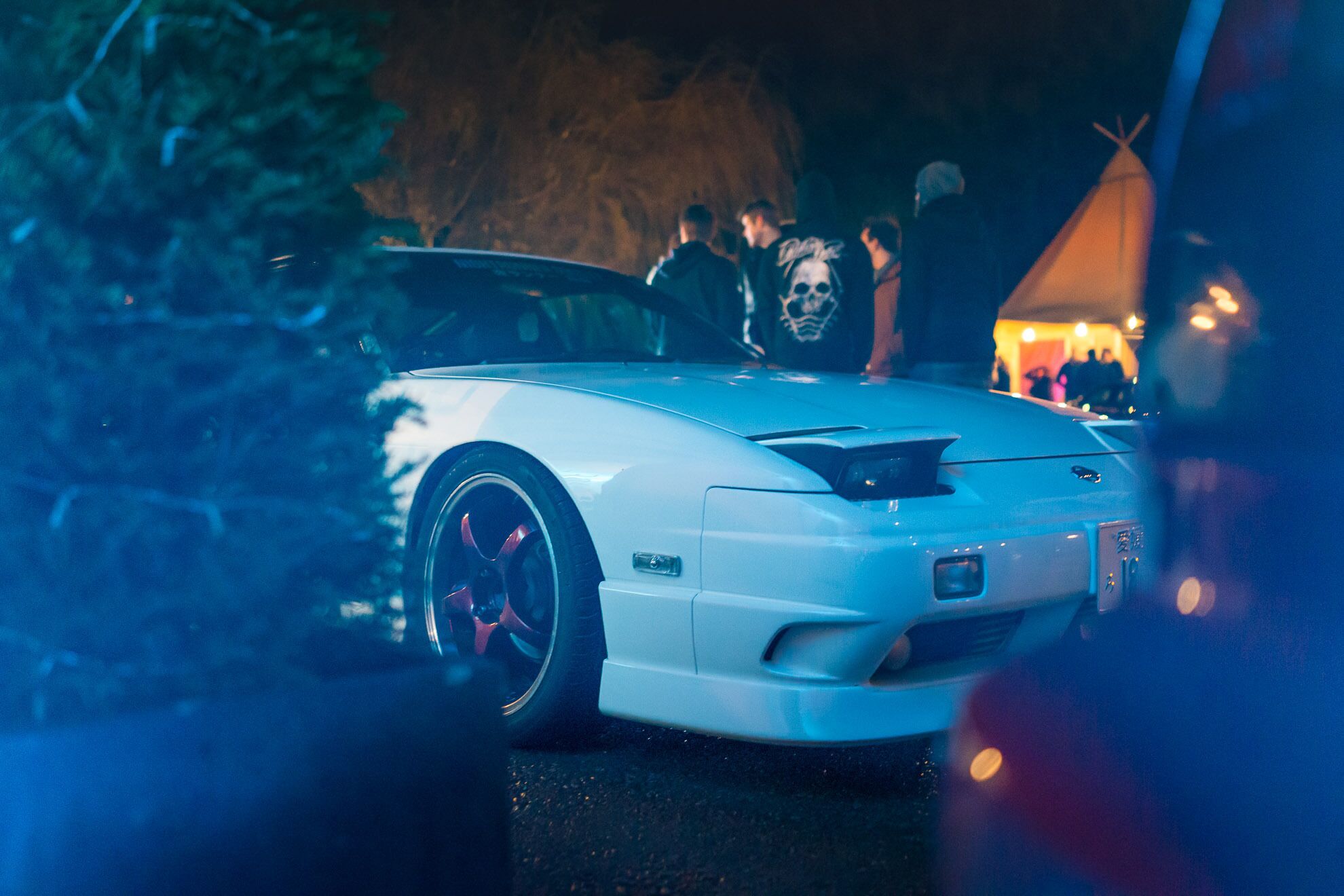 A white sports car parked outdoors at night.