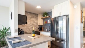 Een moderne keuken met een roestvrijstalen koelkast, een inbouwoven en een klein eiland met een fles champagne.