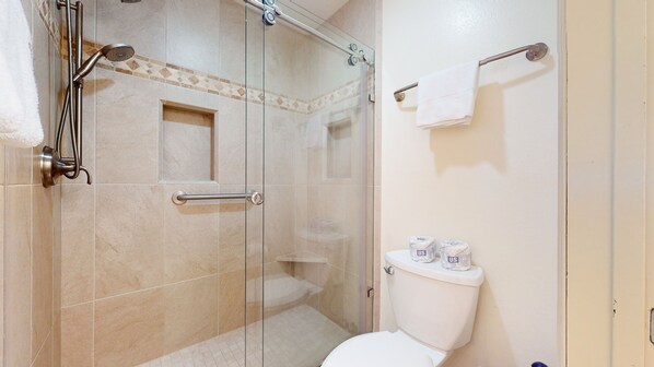 Une salle de bain moderne avec une douche à parois de verre, des toilettes blanches et un porte-serviettes.