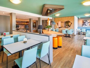 Un restaurant moderne doté d’un bar, de chaises bleu clair et de tables en bois.