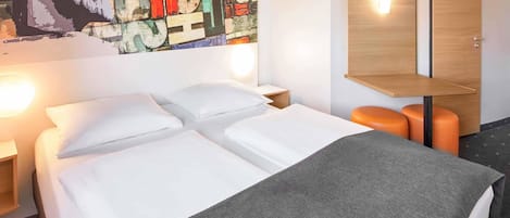 Une chambre d’hôtel comprenant un lit, une table de chevet, une commode, un bureau et une chaise.