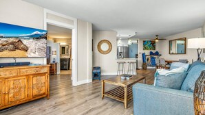 Un salon comprenant un meuble en bois, un canapé bleu, une table basse et un téléviseur diffusant une image d’une tortue de mer.