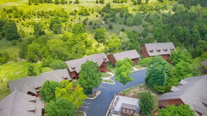 An aerial view of a resort with multiple cabins, a swimming pool, and surrounding greenery.