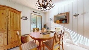 A dining area with a wooden table, chairs, a chandelier, and a large mirror on the wall. - Pet Friendly, Bright & Rustic, Walk to Eagle Lodge & Slopes, Complex Hot Tub (Mammoth Lakes)
