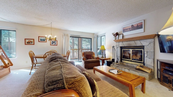 A cozy living room with a fireplace, a sofa, a coffee table, and a television.