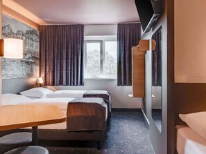 A hotel room with a bed, bedside table, and a window with curtains. - B&B Hotel Oldenburg (Oldenburg)