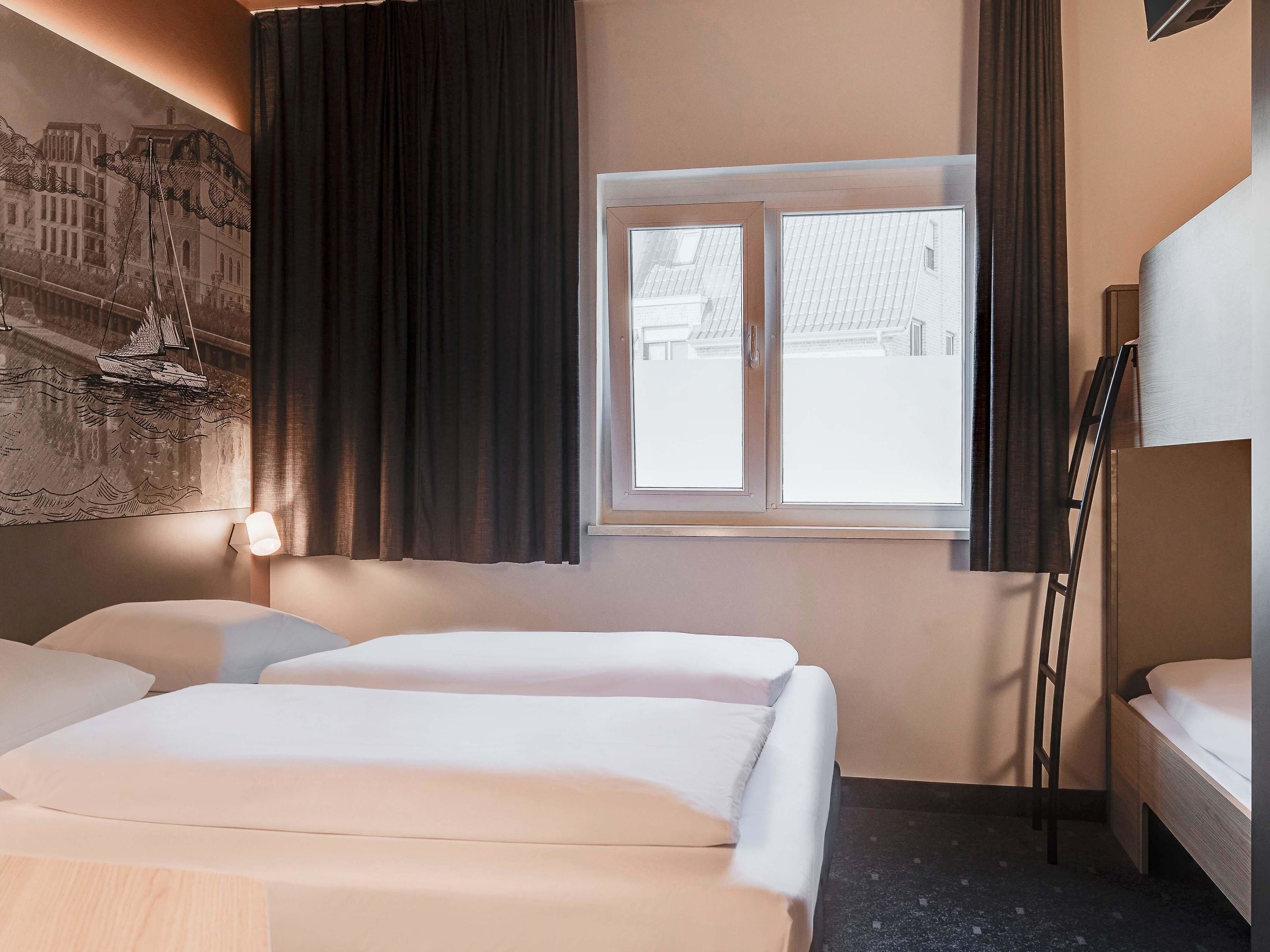 Une chambre d’hôtel avec deux lits, une fenêtre avec des rideaux, un tableau accroché au mur et une échelle appuyée contre le mur.