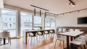 Una sala de conferencias moderna con una larga mesa, múltiples sillas y una mesa central.