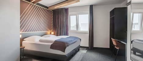 Una habitación de hotel moderna con cama, escritorio y ventana grande.