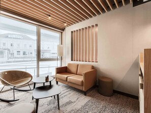 A modern living room with a sofa, a rocking chair, a small table, and a lamp. - B&B Hotel Oldenburg (Oldenburg)