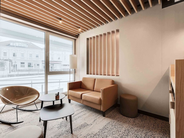 A modern living room with a sofa, a rocking chair, a small table, and a lamp. - B&B Hotel Oldenburg (Oldenburg)
