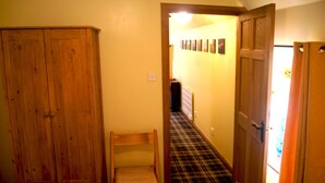A narrow hallway with a wooden wardrobe, a chair, and a door leading to another room. - Sunflower Cottage A Cosy, Pet Friendly place to stay. (Huntly)