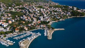 An aerial view of a coastal town with a marina, dense housing, and a hilly backdrop. - "Villa Karmen Split, Private Garden & Heated Pool (Podstrana)