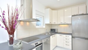 A modern kitchen with white cabinets, stainless steel appliances, and a grey countertop. - "Villa Karmen Split, Private Garden & Heated Pool (Podstrana)