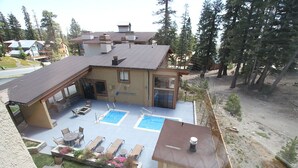 Un bâtiment à deux étages doté d’un patio comprenant deux piscines, des espaces de détente en plein air et un jardin clos.