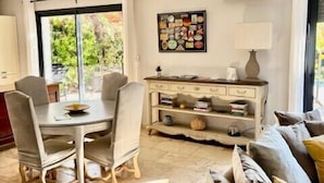A spacious living room with a dining area, a sofa, a coffee table, and a wall-mounted air conditioner.