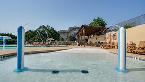 A swimming pool area with clear water, lounge chairs, and a covered seating area. - Spacious 3-bedroom golf condo in the scenic Pointe Royale Golf Resort (Branson)