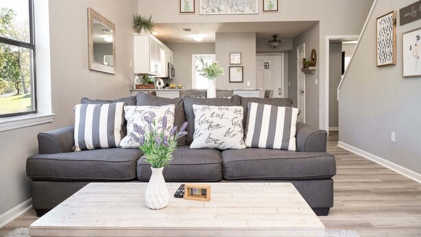 A living room with a gray sofa, a white vase with flowers, and a wooden coffee table. - Spacious 3-bedroom golf condo in the scenic Pointe Royale Golf Resort (Branson)