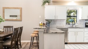 A kitchen with white cabinets, a marble countertop, and a window with a view of trees. - Spacious 3-bedroom golf condo in the scenic Pointe Royale Golf Resort (Branson)