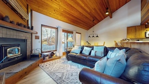Un salon chaleureux avec une cheminée, un canapé en cuir et un coin repas doté de meubles en bois.