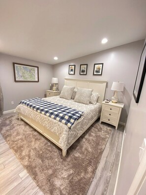 Un dormitorio con una cama grande, dos mesitas de noche y una alfombra.