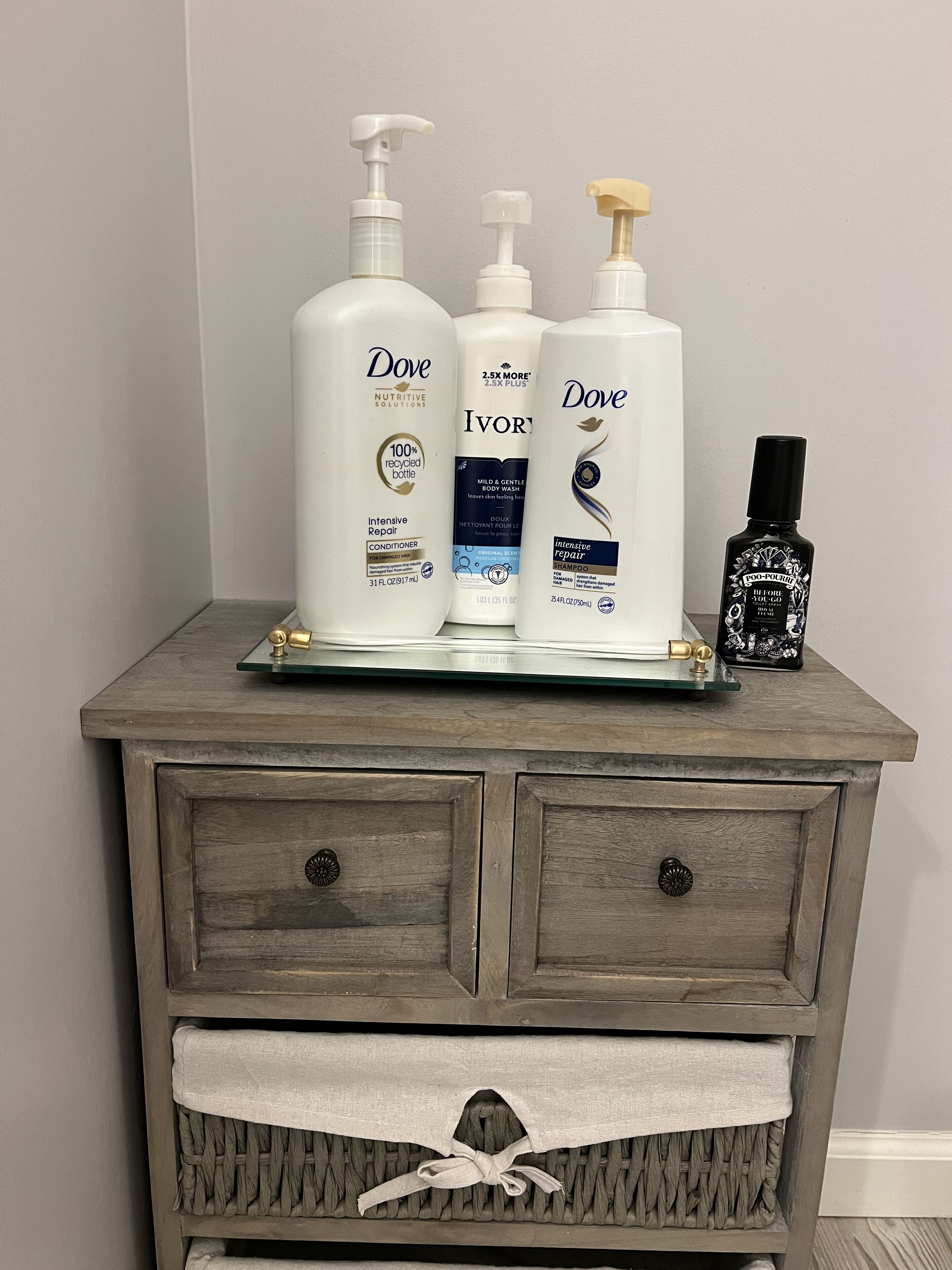 A wooden dresser with three Dove personal care products and a black bottle of hair product.