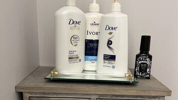 A wooden dresser with three Dove personal care products and a black bottle of hair product.