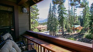 A wooden balcony with a view of a forest and mountains. - Spacious & Updated. Across from The Village, Private Balcony & Gas Grill (Mammoth Lakes)