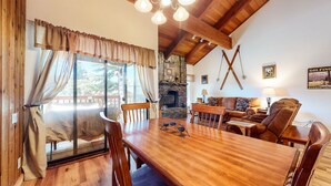 Una habitació acollidora amb una taula de dinar de fusta, cadires, una llar de pedra i un sofà.