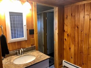 A wooden bathroom with a granite sink, a mirror, and a towel hanging on the wall. - Direct Trail Access-L & R Lakeside Rentals with this Beautiful Camp on Long Lake (Sinclair)