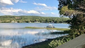 A lakeside view with a dock and a boat. - Direct Trail Access-L & R Lakeside Rentals with this Beautiful Camp on Long Lake (Sinclair)