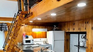 A kitchen with wooden paneling, a granite countertop, a sink, a stove, and a refrigerator. There are wooden chairs and a staircase leading to an upper level. - Direct Trail Access-L & R Lakeside Rentals with this Beautiful Camp on Long Lake (Sinclair)
