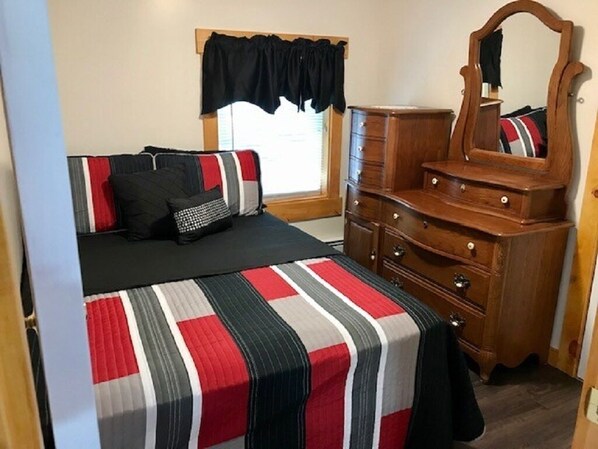 Een slaapkamer met een bed, een kaptafel, een spiegel en een raam met gordijnen.