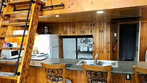 A wooden interior with a kitchen area, including a coffee station and a ladder. - Direct Trail Access-L & R Lakeside Rentals with this Beautiful Camp on Long Lake (Sinclair)
