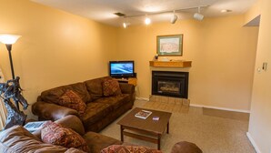 A living room with a brown sofa, a coffee table, a fireplace, and a television. - Alpine Condo | 2 Bedroom | Walk to Lifts | Very Convinient (Mt. Crested Butte)