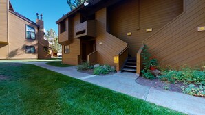 A modern building with a wooden exterior, a staircase leading to the entrance, and a well-maintained lawn. - Large Home, Balcony. Pool & Tennis Court On-site, Short Walk to Restaurants (Mammoth Lakes)