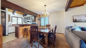 Une cuisine chaleureuse avec des meubles en bois, un coin bar et une table à manger avec des chaises.