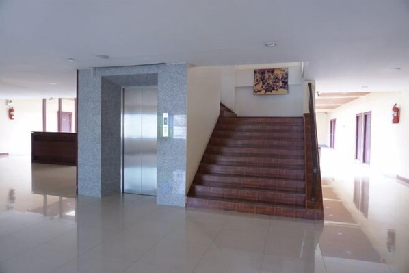 A hotel lobby with a staircase, a reception desk, and a fire extinguisher. - King Hotel (Loei)