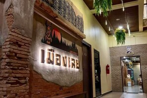 A hotel entrance with a rustic brick wall and a sign that reads 'IWAVE'. - King Hotel (Loei)